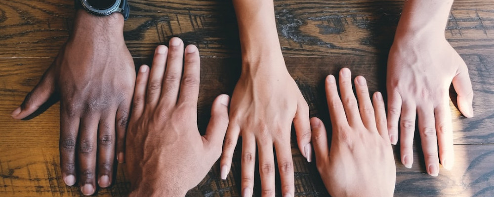 A selection of intertwined hands from different ethnic backgrounds.